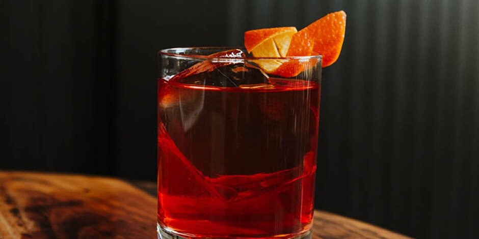 Negroni cocktail in a rocks glass on a dark wood table.